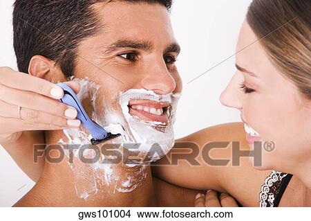 Picture - Close-up of a young woman shaving a mid adult man. Fotosearch