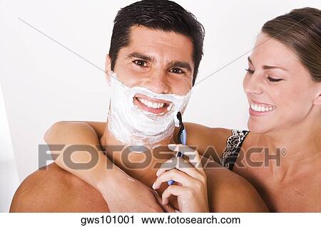 Stock Image - Close-up of a young woman shaving a mid adult man. Fotosearch