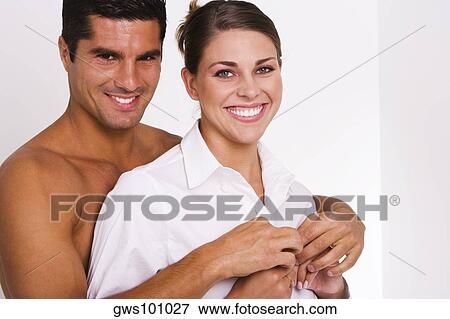 Stock Photo - Portrait of a mid adult man buttoning a young woman's shirt. Fotosearch