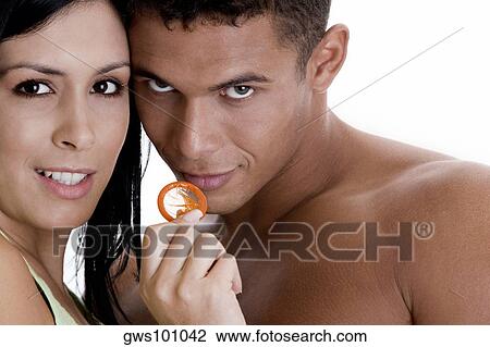 Stock Image - Portrait of a young couple holding a condom. Fotosearch