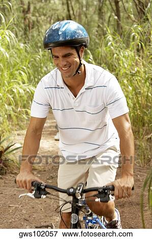 Stock Photo - Mid adult man riding a bicycle and smiling. Fotosearch