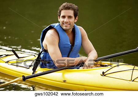 Stock Image - Portrait of a mid adult man sitting in a kayak. Fotosearch