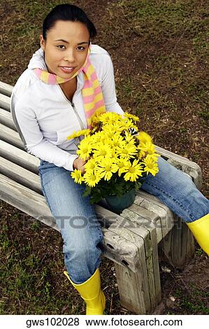 Portrait of a young woman sitting on a bench with a vase View Large Photo Image Stock Photo - Portrait of a young woman sitting on a bench with a vase. Fotosearch