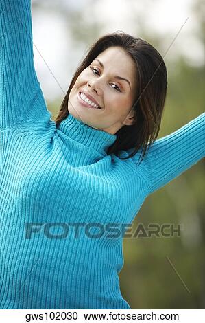 Portrait of a young woman smiling with her arms raised View Large Photo Image Stock Image - Portrait of a young woman smiling with her arms raised. Fotosearch