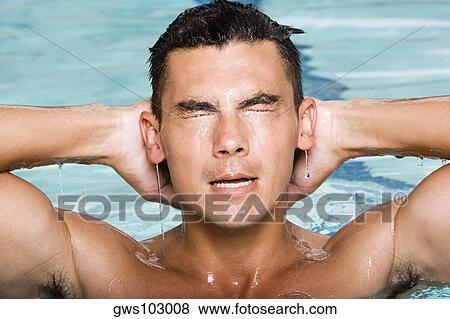 Close-up of a young man splashing water in a swimming pool View Large Photo Image Stock Photo - Close-up of a young man splashing water in a swimming pool. Fotosearch