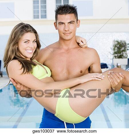 Portrait of a young man carrying a young woman at the poolside View Large Photo Image Stock Photo - Portrait of a young man carrying a young woman at the poolside. Fotosearch