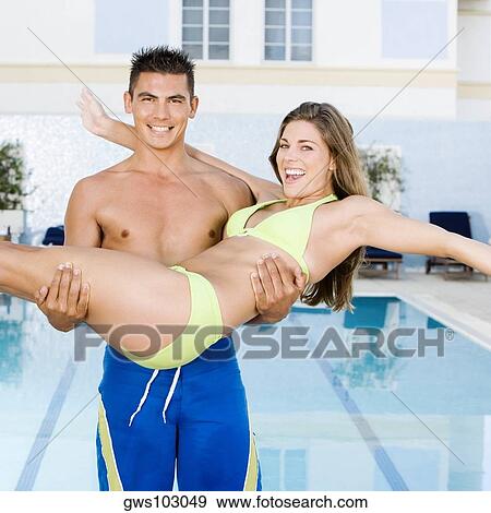 Portrait of a young man carrying a young woman at the poolside View Large Photo Image Stock Photo - Portrait of a young man carrying a young woman at the poolside. Fotosearch