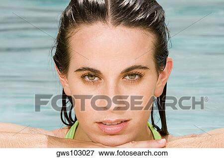 Stock Photo - Portrait of a young woman leaning at the edge of a swimming pool. Fotosearch