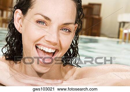 Stock Image - Portrait of a young woman smiling in a swimming pool. Fotosearch