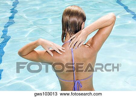 Stock Image - Rear view of a young woman in a swimming pool. Fotosearch