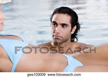 Side profile of a young woman lying down at the poolside with a mid adult man in the swimming pool View Large Photo Image Stock Photo - Side profile of a young woman lying down at the poolside with a mid adult man in the swimming pool. Fotosearch