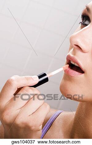 Close-up of a young woman applying lipstick on her lips View Large Photo Image Stock Photo - Close-up of a young woman applying lipstick on her lips. Fotosearch