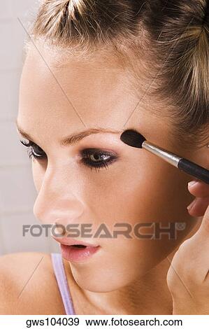 Close-up of a young woman applying eyeshadow View Large Photo Image Stock Photo - Close-up of a young woman applying eyeshadow. Fotosearch
