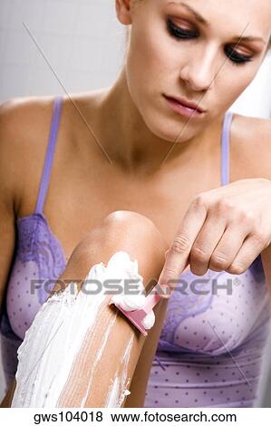 Stock Photo - Close-up of a young woman shaving her legs. Fotosearch