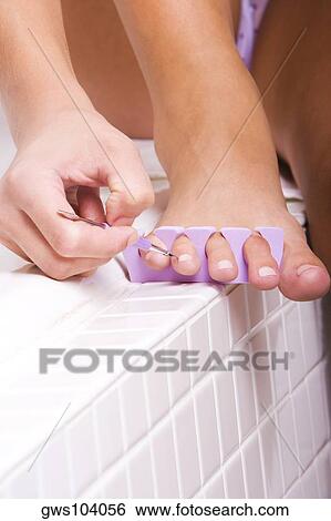 Low section view of a young woman painting her toenails View Large Photo Image Stock Photograph - Low section view of a young woman painting her toenails. Fotosearch