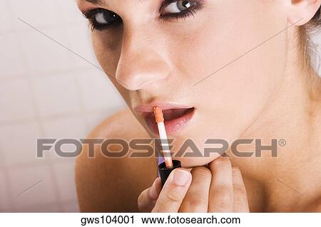 Portrait of a young woman applying lip liner View Large Photo Image Stock Image - Portrait of a young woman applying lip liner. Fotosearch
