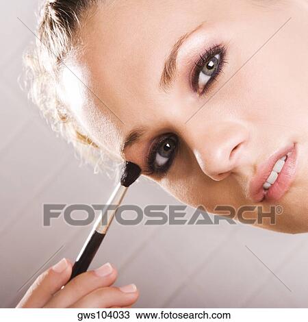 Portrait of a young woman applying eyeshadow View Large Photo Image Stock Image - Portrait of a young woman applying eyeshadow. Fotosearch