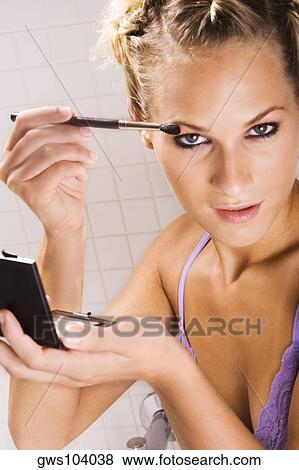 Stock Photo - Portrait of a young woman applying eyeshadow. Fotosearch