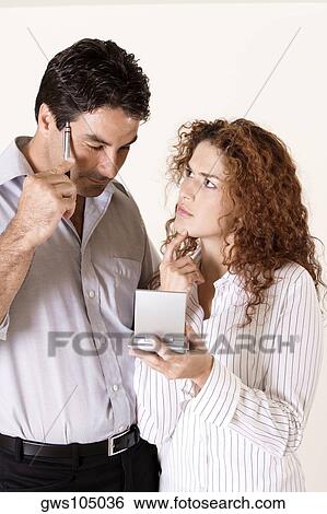 Close-up of a young woman and a mid adult man using a calculator View Large Photo Image Stock Photograph - Close-up of a young woman and a mid adult man using a calculator. Fotosearch