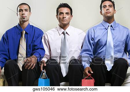 Stock Photograph - Close-up of three businessmen sitting side by side. Fotosearch