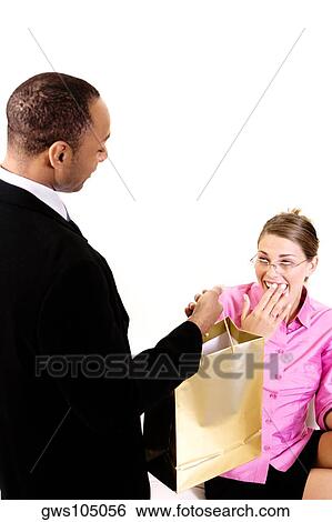 Stock Photograph - High angle view of a young man holding a bag in front of a young woman. Fotosearch