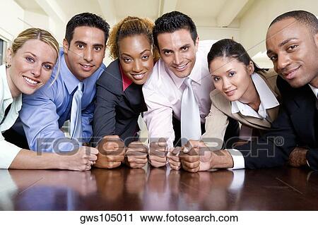 Stock Image - Portrait of a group of business executives with their fists on a table. Fotosearch