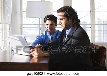 Two businessmen working on a laptop View Large Photo Image Stock Image - Two businessmen working on a laptop. Fotosearch