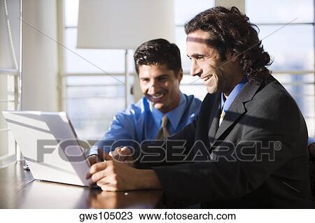 Two businessmen working on a laptop View Large Photo Image Stock Image - Two businessmen working on a laptop. Fotosearch