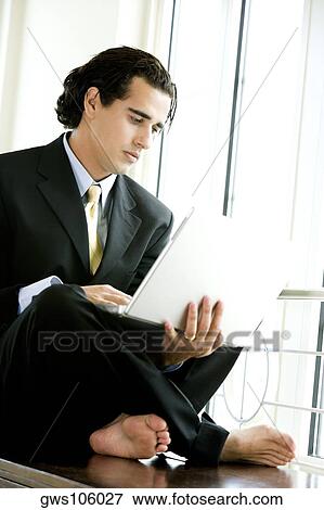 Stock Photo - Businessman sitting and using a laptop. Fotosearch