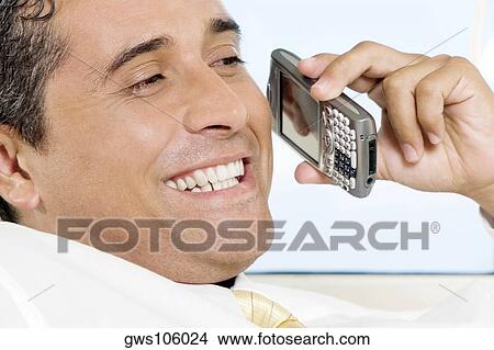 Close-up of a businessman holding a mobile phone smiling View Large Photo Image Picture - Close-up of a businessman holding a mobile phone smiling. Fotosearch