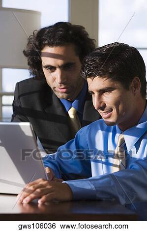 Close-up of two businessmen working on a laptop View Large Photo Image Stock Photograph - Close-up of two businessmen working on a laptop. Fotosearch