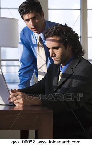 Stock Image - Two businessmen using a laptop. Fotosearch
