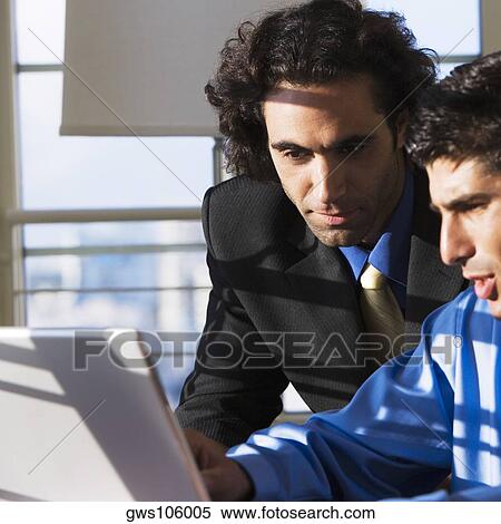 Stock Photography - Two businessmen using a laptop. Fotosearch