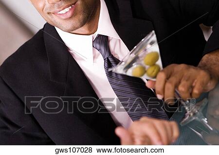 Close-up of a businessman holding a martini glass View Large Photo Image Stock Photo - Close-up of a businessman holding a martini glass. Fotosearch