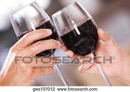 Stock Image - Close-up of a man and a woman toasting glasses of red wine. Fotosearch