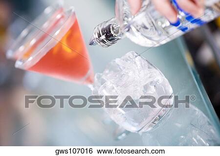 Stock Photograph - Close-up of a person's hand pouring white wine into a wineglass. Fotosearch