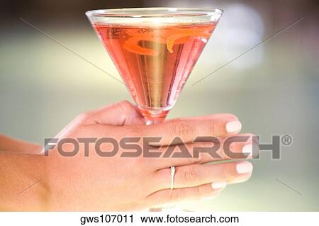 Close-up of a woman's hand holding a glass of martini View Large Photo Image Stock Image - Close-up of a woman's hand holding a glass of martini. Fotosearch