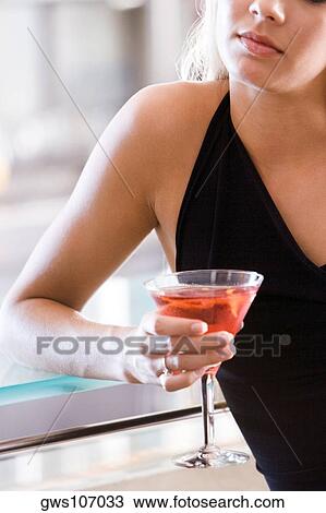 Close-up of a young woman holding a glass of martini View Large Photo Image Stock Image - Close-up of a young woman holding a glass of martini. Fotosearch