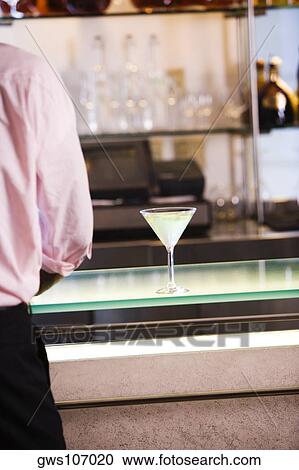 Stock Image - Mid section view of a businessman standing at a bar counter. Fotosearch