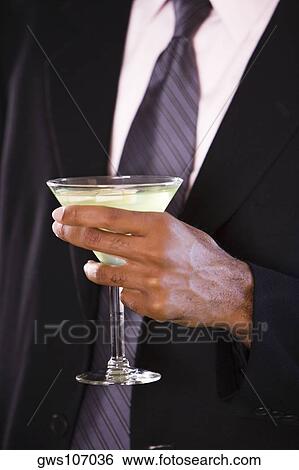 Mid section view of a businessman holding a glass of martini View Large Photo Image Stock Photograph - Mid section view of a businessman holding a glass of martini. Fotosearch