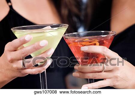 Stock Photo - Mid section view of two young women toasting martinis. Fotosearch