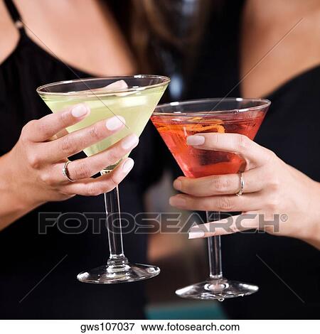 Stock Photo - Mid section view of two young women toasting martinis. Fotosearch
