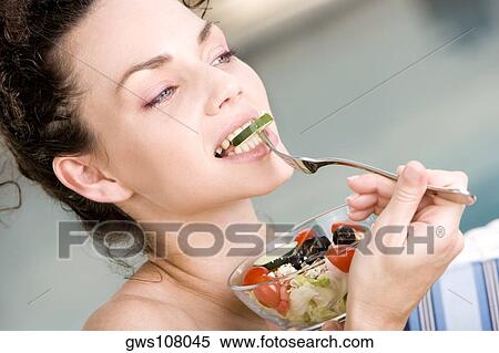 Stock Photography - Close-up of a young woman eating salad with a fork. Fotosearch