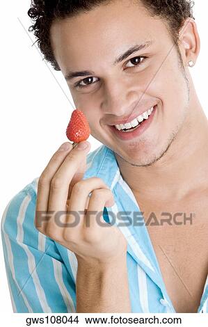 Portrait of a young man holding a strawberry View Large Photo Image Picture - Portrait of a young man holding a strawberry. Fotosearch