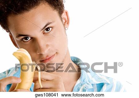 Stock Image - Portrait of a young man peeling a banana. Fotosearch