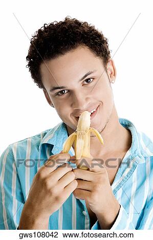Stock Image - Portrait of a young man peeling a banana. Fotosearch