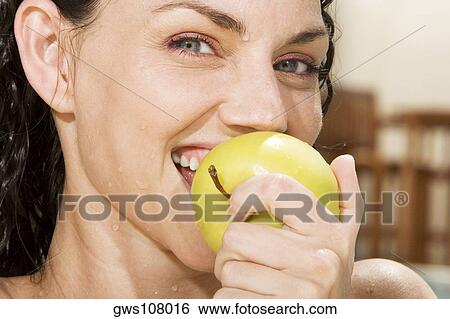 Stock Photograph - Portrait of a young woman eating a green apple. Fotosearch