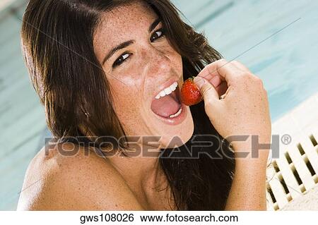 Portrait of a young woman eating a strawberry View Large Photo Image Stock Photograph - Portrait of a young woman eating a strawberry. Fotosearch