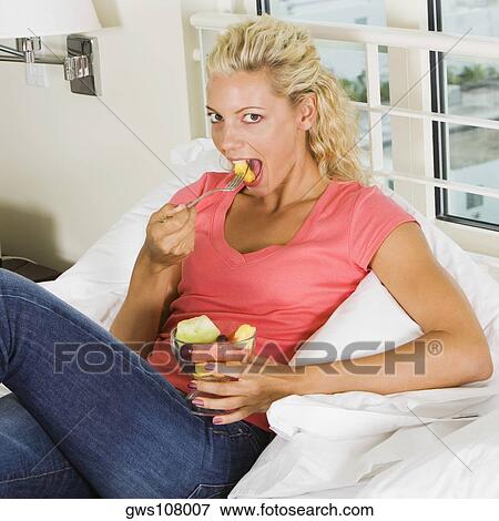 Portrait of a young woman eating fruit salad View Large Photo Image Stock Photo - Portrait of a young woman eating fruit salad. Fotosearch