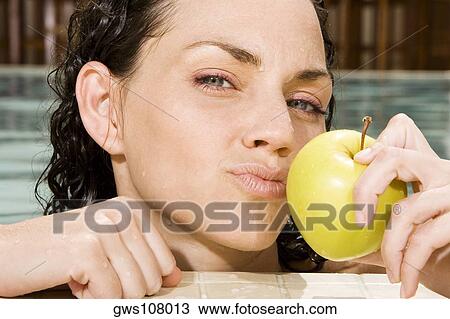 Portrait of a young woman holding a green apple in a swimming pool View Large Photo Image Stock Image - Portrait of a young woman holding a green apple in a swimming pool. Fotosearch